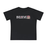 Believe Baby Tee features BELIEVE in white, with a pink-bow I and gingerbread-house E, on a soft, durable black T-shirt.