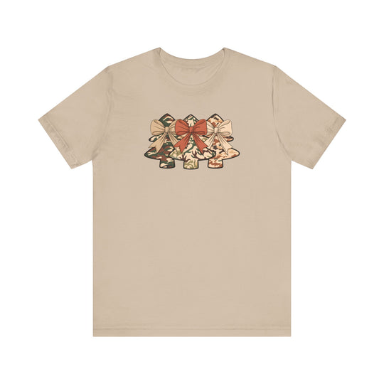 Camo Christmas Tree Tee: Light-tan T-shirt with three camouflage-patterned Christmas trees, each topped with bows. Classic fit, soft cotton, ribbed collar, dual seams for shape retention.