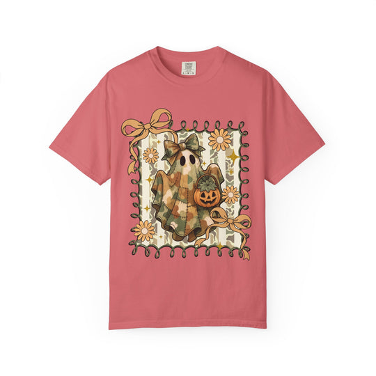 Quilted Ghost Tee: Coral-pink T-shirt featuring a ghost in camo fabric with a jack-o'-lantern, daisies, ribbons, and stars in a square-frame Halloween illustration.