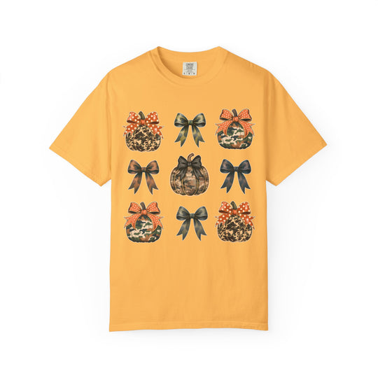 Bows and Pumpkins Tee features a 3×3 grid of camo-patterned pumpkins and bows on a mustard-yellow T-shirt, highlighting a fall-themed, unique graphic design.