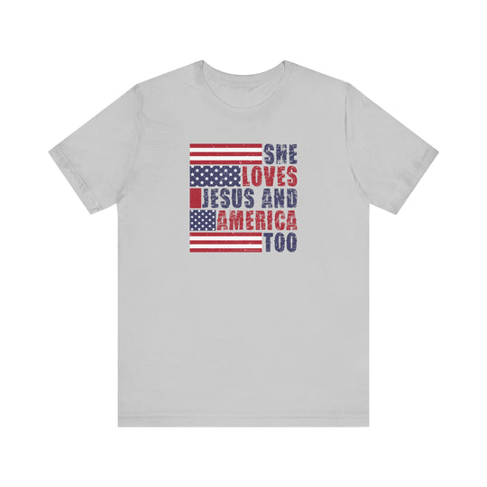 A classic She Loves Jesus and America Tee, unisex jersey shirt with red and blue text. Soft cotton, ribbed knit collars, tear away label, and retail fit. Sizes XS to 3XL.