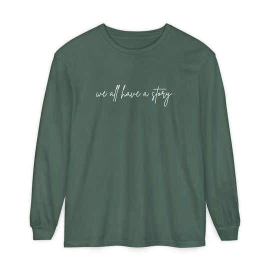 We all have a Story Long Sleeve Tee: green, long-sleeved shirt featuring white text, made from 100% ring-spun cotton with a relaxed fit.