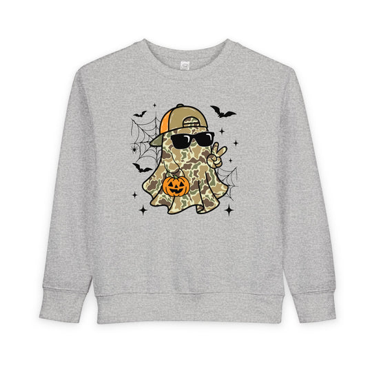 Candy Ghost Toddler Crew sweatshirt features a camo-clad ghost with sunglasses, peace sign, and pumpkin bucket, surrounded by spiderwebs, bats, and sparkles. Cozy and durable design.