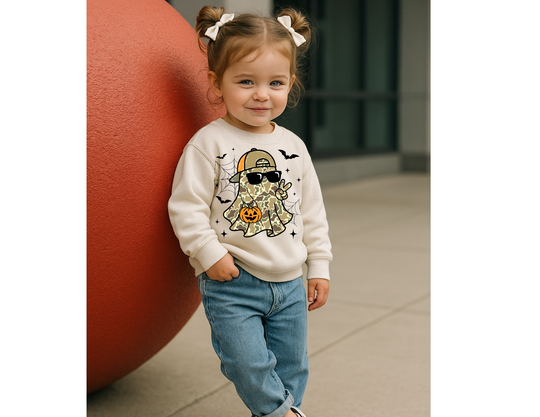Toddler wearing Candy Ghost Toddler Crew sweatshirt with cartoon ghost design, standing outdoors by a giant red sphere. Perfect blend of comfort and style for kids.