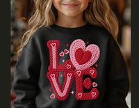 Young girl wearing the Love Heart Toddler Crew sweatshirt, featuring a knitted-style LOVE graphic with overlapping heart-shaped O, surrounded by tiny hearts and sparkles.