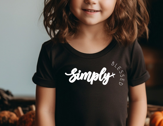 Simply Blessed Toddler's Tee: A smiling girl in a comfortable tee, designed for softness and durability, ideal for toddlers' sensitive skin and everyday adventures.