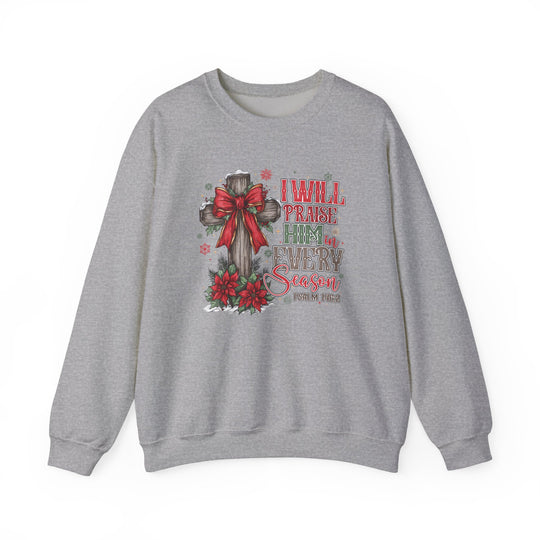 Light-grey crewneck sweatshirt featuring a Christmas-themed design with a wooden cross, evergreen sprigs, and festive text: “Praise Him in Every Season, Psalm 145:2.”