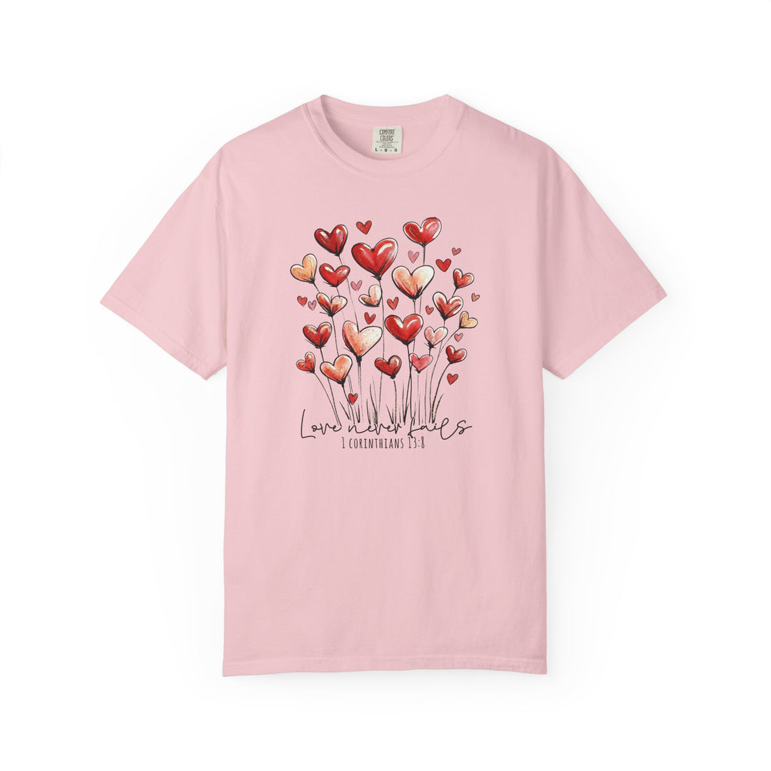 Light pink tee with heart-shaped flowers and Love never fails, 1 Corinthians 13:8 graphic from Faith Family Designs.