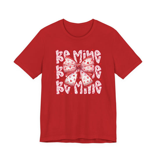 Red Be Mine Tee featuring a Valentine's-themed graphic with a pink and white heart-patterned bow over repeating BE MINE text, crafted from soft cotton.