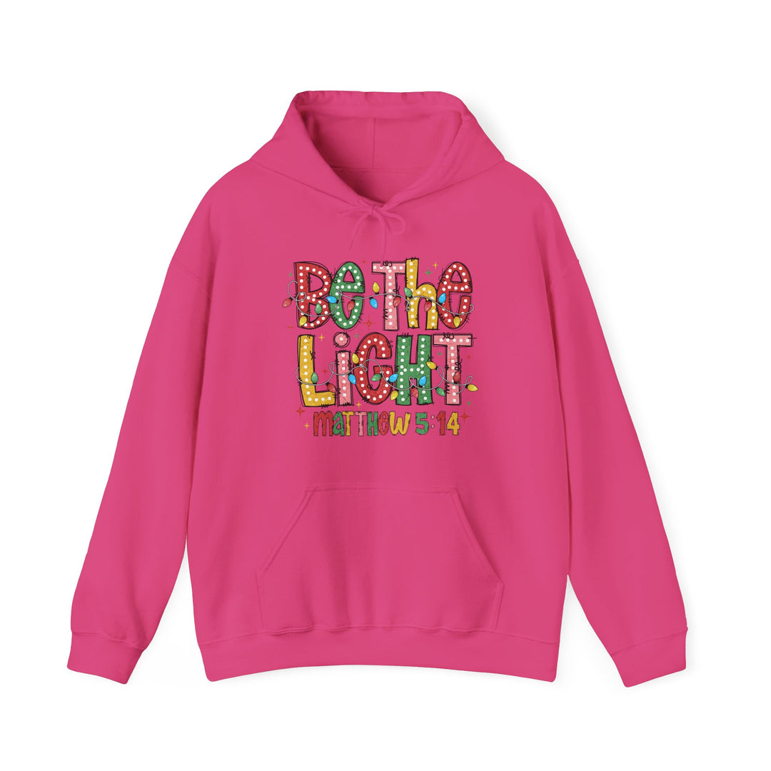 Bright pink Be the Light hoodie with hand-lettered chest design, featuring Christmas lights and verse Matthew 5:14, kangaroo pocket, and drawstring hood.