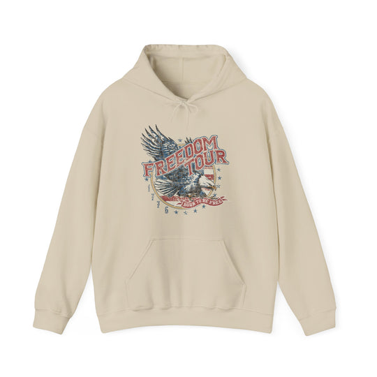 A beige hoodie with a graphic design, the Freedom Tour Hoodie by Worlds Worst Tees. Unisex heavy blend, cotton-polyester fabric, kangaroo pocket, and drawstring hood. Medium-heavy fabric, tear-away label, true to size.