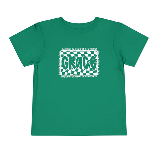 Grace Toddler Tee: A green shirt featuring white text, crafted from 100% Airlume combed cotton for toddlers, offering comfort with a tear-away label.