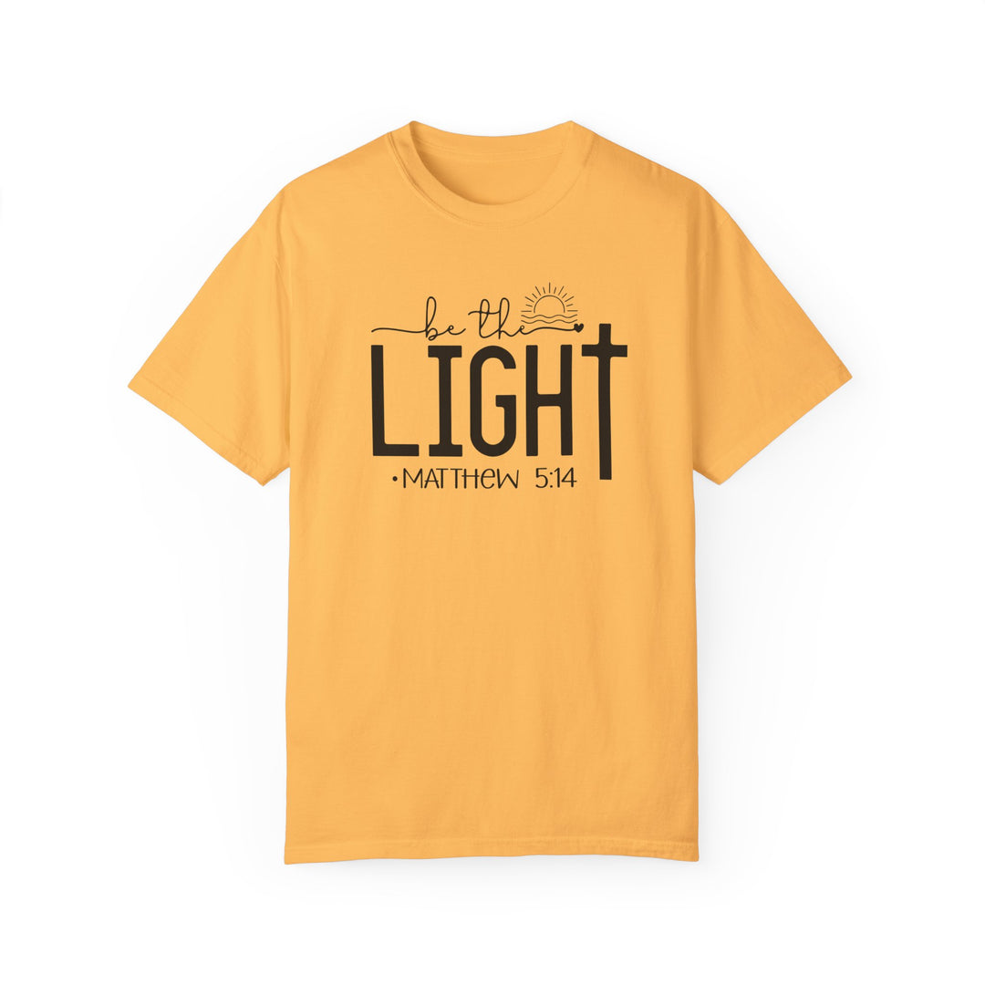 A relaxed fit Be the Light Tee, a yellow shirt with black text, crafted from 100% ring-spun cotton. Medium weight, garment-dyed for coziness, featuring durable double-needle stitching and a seamless design.