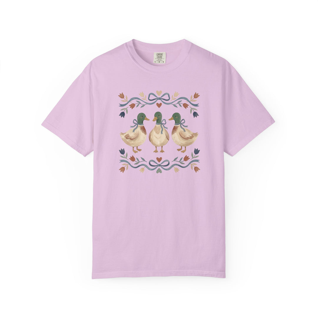 Light lavender Cottagecore Tee with folk-art motif of three mallard ducks with bows, framed by floral swags and tulip-like blossoms, on soft, durable cotton.