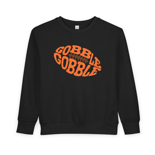 Gobble Football Toddler Crew: Black sweatshirt with GOBBLE GOBBLE graphic in an orange football shape, offering warmth and comfort for toddlers.