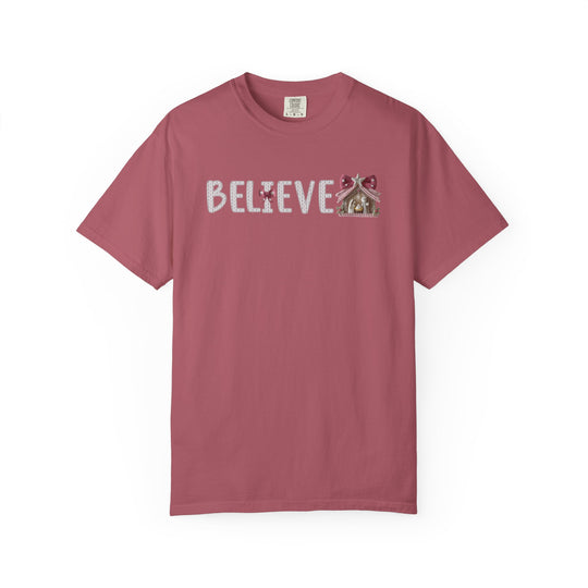 Believe Tee featuring a festive design with BELIEVE in white yarn font and a gingerbread-house ornament replacing the final E on a soft crew-neck shirt.