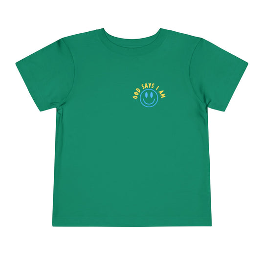 I AM Toddler Tee featuring a blue smiley-face graphic and GOD SAYS I AM. text on a green background, made from soft cotton for comfort.
