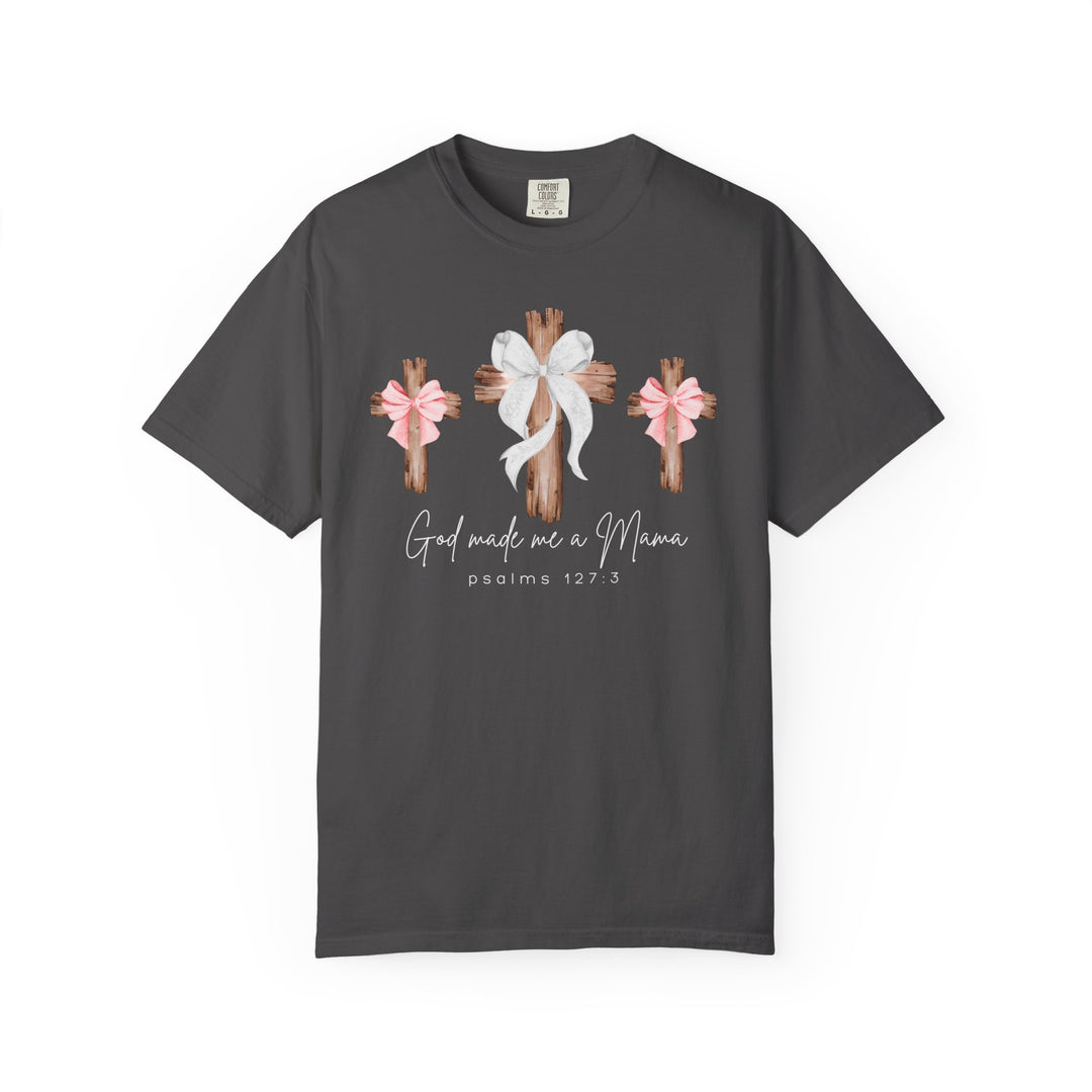 Charcoal-gray tee with three wooden crosses, center cross with white bow, flanking pink bows, script text “God made me a Mama” with “psalms 127:3.”