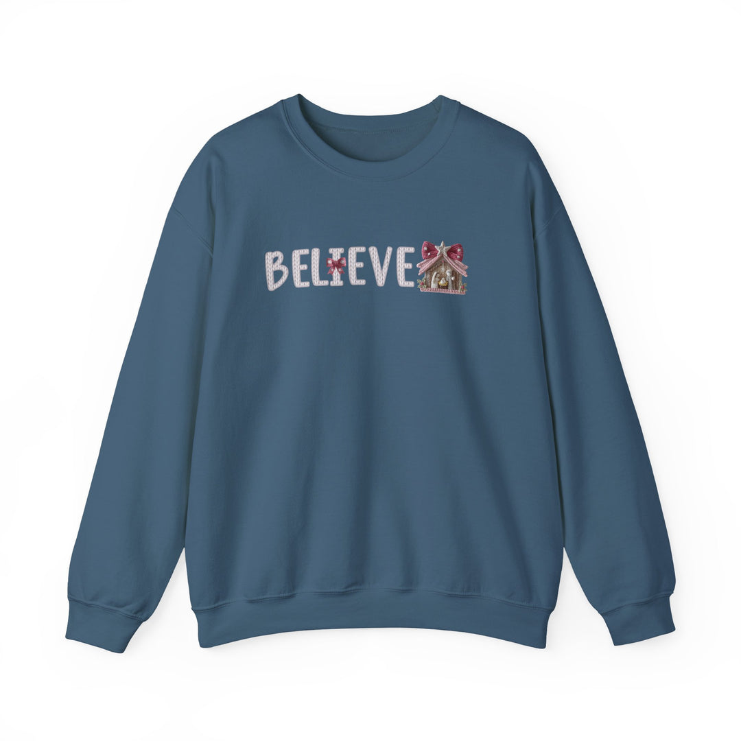 Blue crew-neck sweatshirt with BELIEVE in festive font, featuring a gingerbread-house motif. Cozy, medium-heavy blend, ideal for colder months.