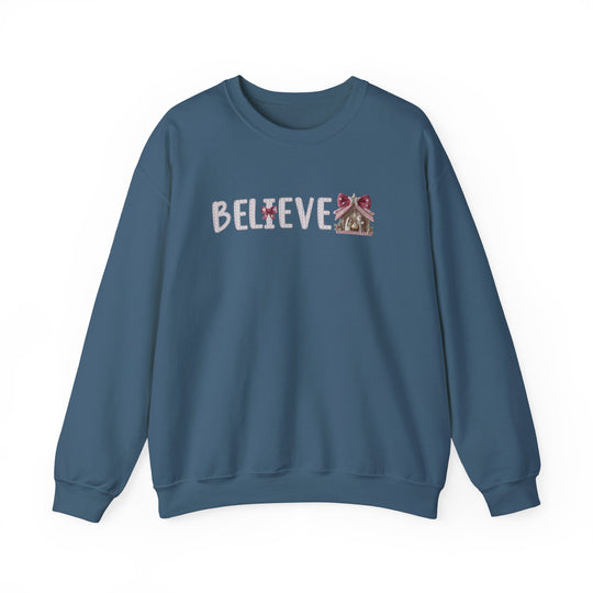 Blue crew-neck sweatshirt with BELIEVE in festive font, featuring a gingerbread-house motif. Cozy, medium-heavy blend, ideal for colder months.