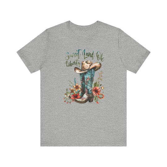 A grey t-shirt featuring a cowboy hat and flowers, part of the Sweet Land of Liberty Tee collection at Worlds Worst Tees. Unisex jersey tee with ribbed knit collars, 100% cotton, and retail fit.