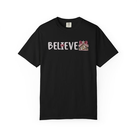 Believe Tee featuring textured BELIEVE lettering and gingerbread house detail on a black Comfort Colors T-shirt, blending comfort and playful design.