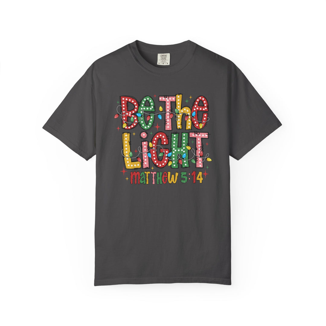 Charcoal Be the Light T-shirt featuring festive light bulb graphics and Matthew 5:14 text, embodying Faith Family Designs' unique, inspirational style.