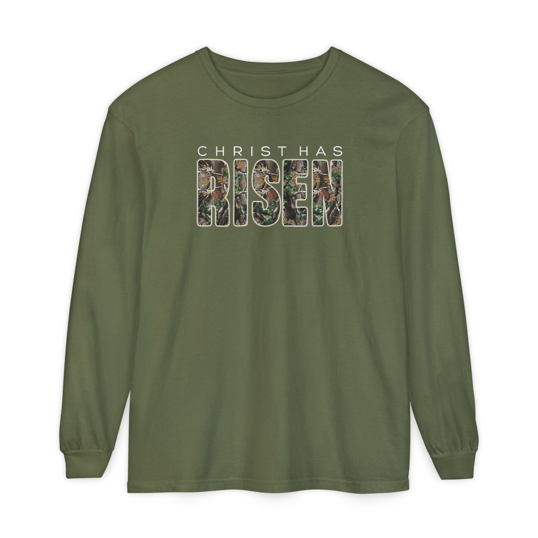 Christ Has Risen Long Sleeve Tee featuring olive-green fabric with CHRIST HAS in white and RISEN in a camouflage pattern, offering comfort with 100% ring-spun cotton.