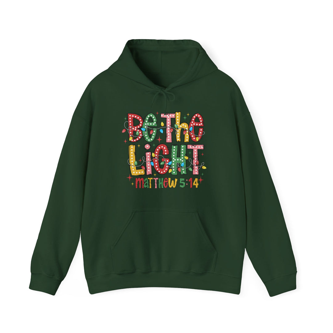 Dark-green Be the Light hoodie with festive graphic and Matthew 5:14 reference, featuring kangaroo pocket and drawstring hood for a cozy, stylish look.