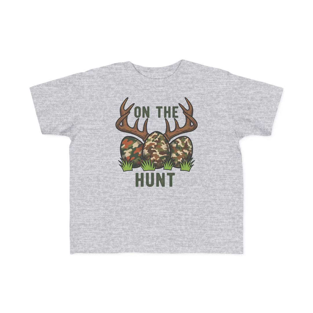 Light-gray toddler tee with 'On the Hunt' graphic of camouflage eggs and deer antlers, perfect for sensitive skin and first adventures.
