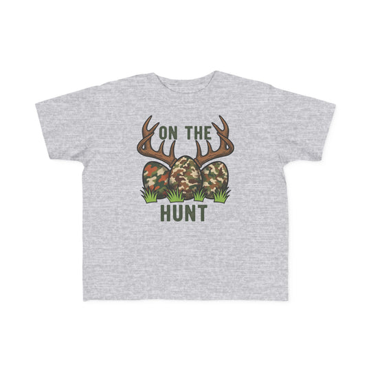 Light-gray toddler tee with 'On the Hunt' graphic of camouflage eggs and deer antlers, perfect for sensitive skin and first adventures.