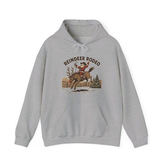 Light-gray Reindeer Rodeo Hoodie featuring Santa as a cowboy riding a reindeer, offering warmth and style with a kangaroo pocket and color-matched drawstrings.