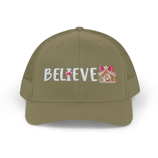 Believe Snapback Trucker Cap (Embroidery) features BELIEVE with a candy-cane I and gingerbread motif, olive-green front, mesh back, and adjustable snap closure.