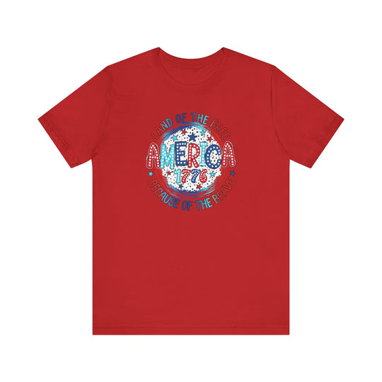 A red America 1776 Tee with a patriotic logo on soft cotton fabric. Unisex fit with ribbed knit collar, taping on shoulders, and tear-away label. Sizes XS to 3XL.