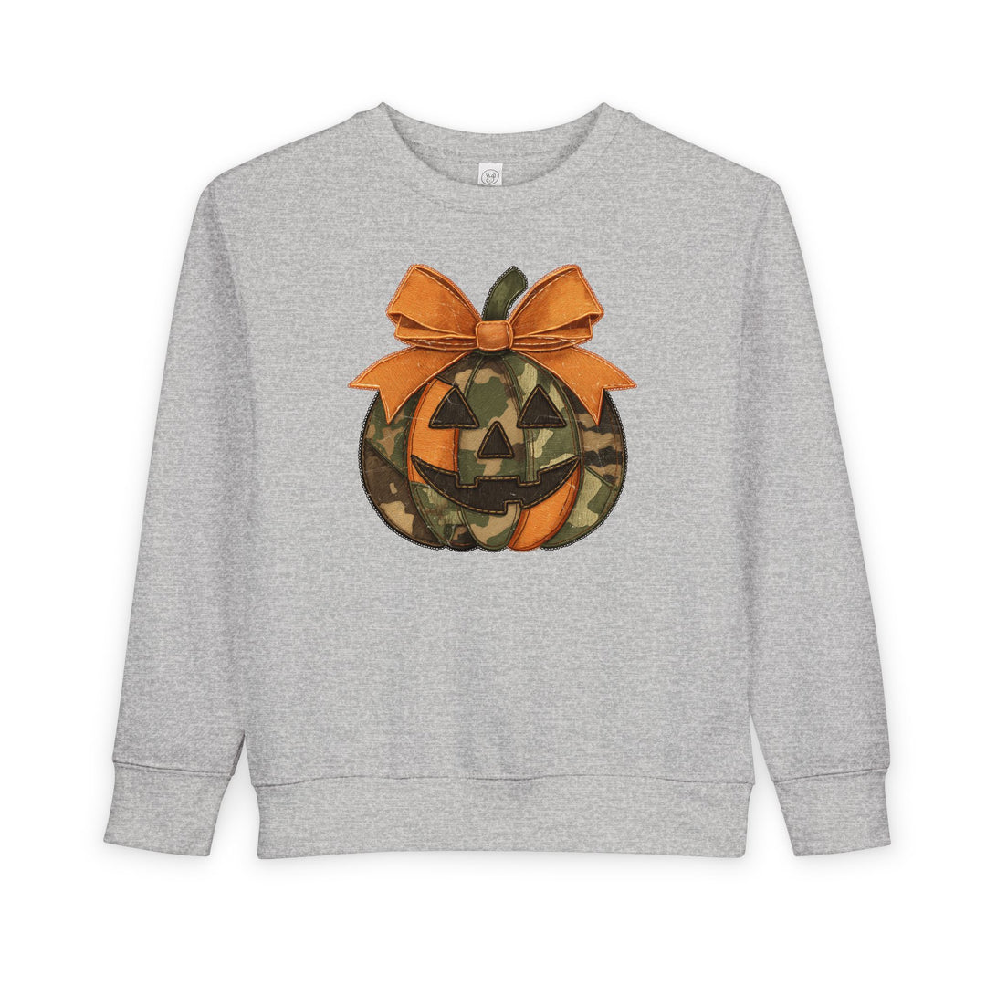 Jackie O Toddler Crew: Light-gray sweatshirt with a camo-patterned jack-o-lantern graphic and stitched orange bow, offering cozy comfort for toddlers.
