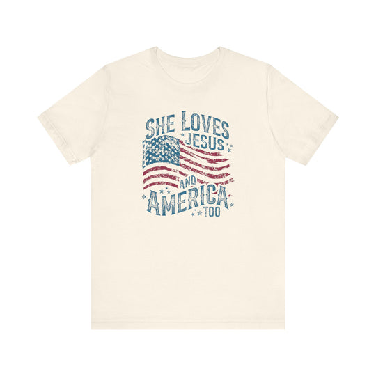 Cream-colored T-shirt with a distressed American-flag motif and She Loves Jesus and America Too slogan, embodying a patriotic and faith-inspired design.