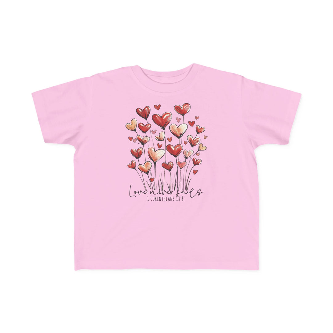 Light-pink toddler tee featuring whimsical heart graphics and Love never fails text, crafted from soft cotton for sensitive skin.