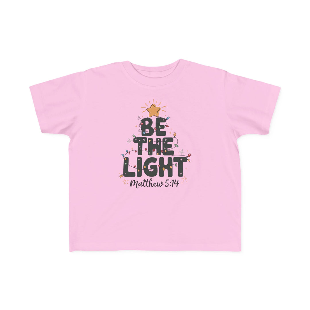 Be the Light Toddler Tee with festive tree graphic, 'BE THE LIGHT' text, and Bible verse Matthew 5:14. Soft, durable, perfect for toddlers' sensitive skin.