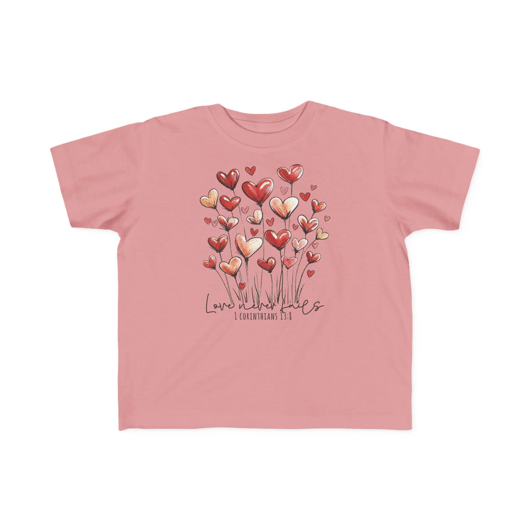 Love Never Fails Toddler Tee: Light-pink T-shirt with heart-shaped blooms and Love never fails text, perfect for toddlers' sensitive skin and first adventures.