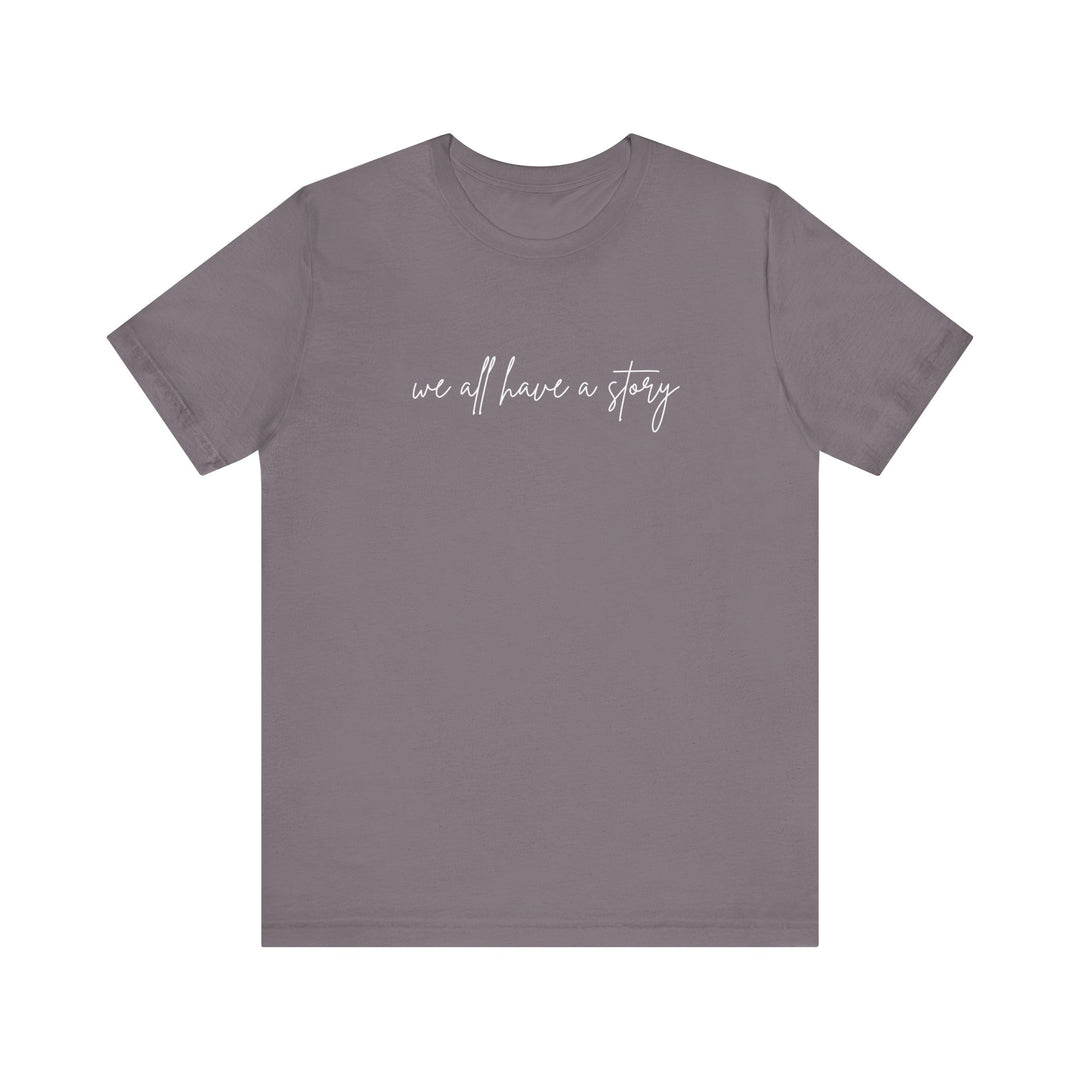 We all have a Story Tee: Grey t-shirt with white text, unisex fit, soft cotton, ribbed knit collar, and tapered shoulders for comfort and style.