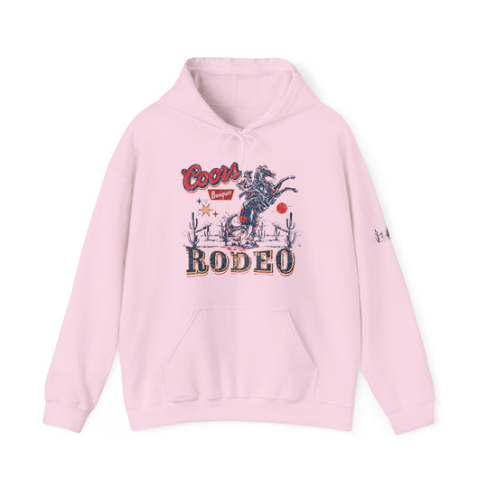 A Coors Rodeo Hoodie, a pink sweatshirt with a cowboy design. Unisex heavy blend, 50% cotton, 50% polyester, kangaroo pocket, drawstring hood, tear-away label. Classic fit, medium-heavy fabric.