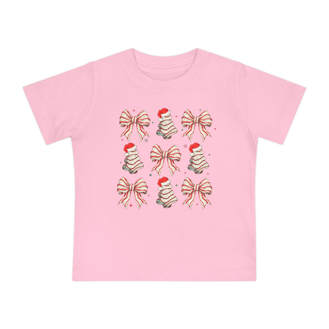 Cookies and Bows Baby Tee: Pink T-shirt with festive icons of bows and Christmas trees. Made for babies, it's super soft, shrink-resistant, and durable.