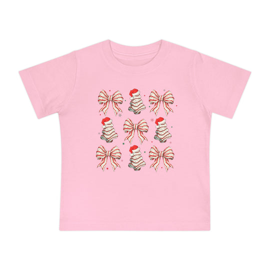 Cookies and Bows Baby Tee: Pink T-shirt with festive icons of bows and Christmas trees. Made for babies, it's super soft, shrink-resistant, and durable.