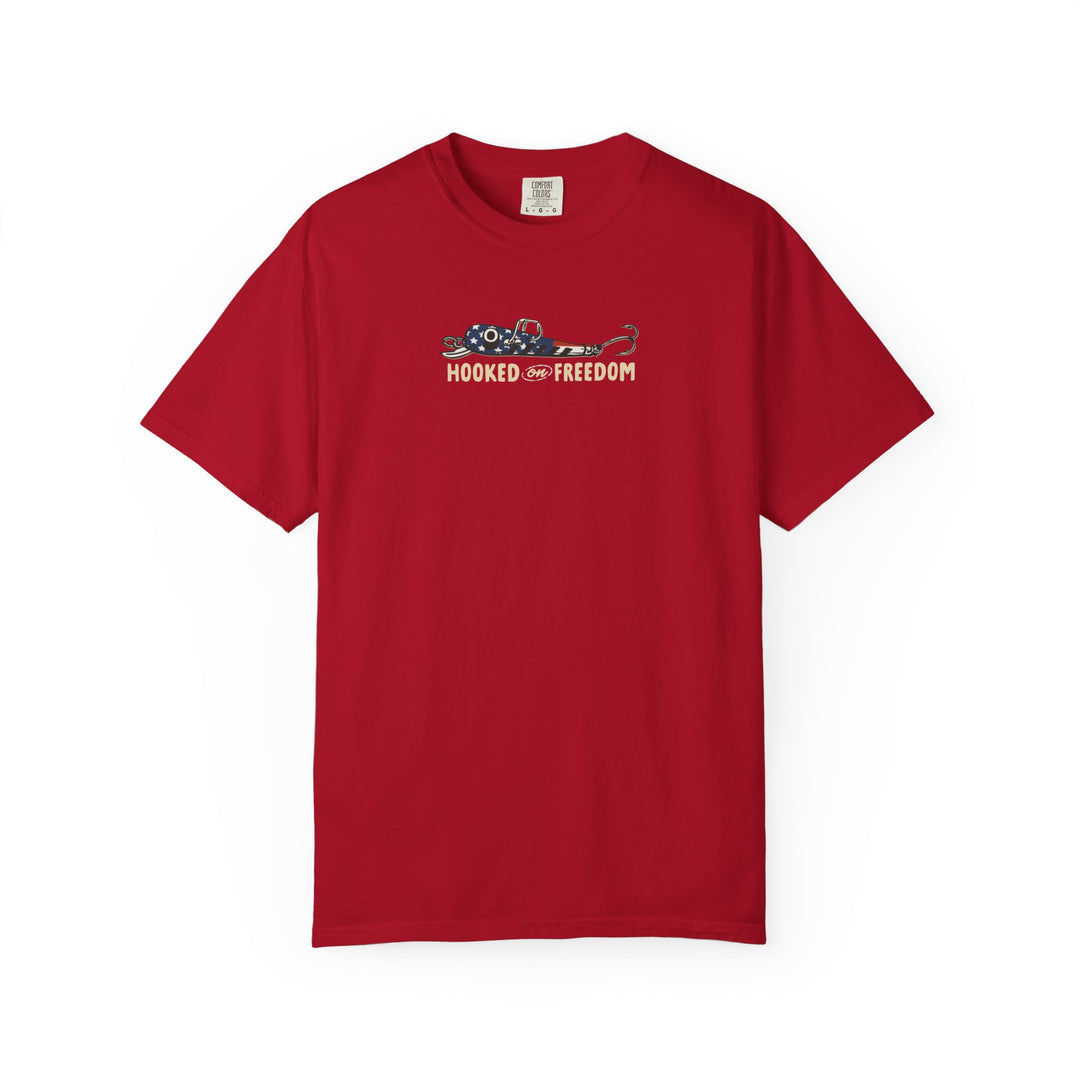 Hooked on Freedom Tee featuring a stylized American-flag fishing lure graphic and slogan, showcased on a Comfort Colors red short-sleeve T-shirt, ideal for relaxed, daily wear.
