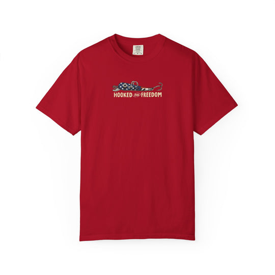 Hooked on Freedom Tee featuring a stylized American-flag fishing lure graphic and slogan, showcased on a Comfort Colors red short-sleeve T-shirt, ideal for relaxed, daily wear.