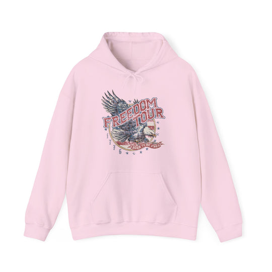 A pink Freedom Tour Hoodie, a cozy blend of cotton and polyester, featuring a graphic design. Unisex, heavy fabric with kangaroo pocket and drawstring hood. Classic fit, tear-away label, true to size.