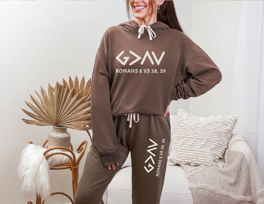 Woman wearing the God is Greater Hoodie - Matching Set, showcasing a relaxed-fit brown sweatshirt with a hood, emphasizing comfort and sustainability in casual wear.