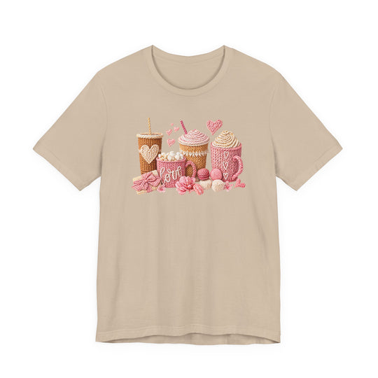 Coffee Love Tee featuring whimsical, yarn-style graphics of warm drinks and treats, crafted on a light-beige T-shirt, embodying cozy charm and quality craftsmanship.