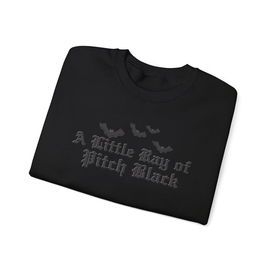 Black sweatshirt folded, featuring A Little Ray of Pitch Black in dark gray old-English font with cartoon bat silhouettes above on the front.