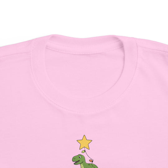 Dino Tree Toddler Tee featuring a cartoon green dinosaur with a star on a light pink shirt, perfect for toddlers' sensitive skin.
